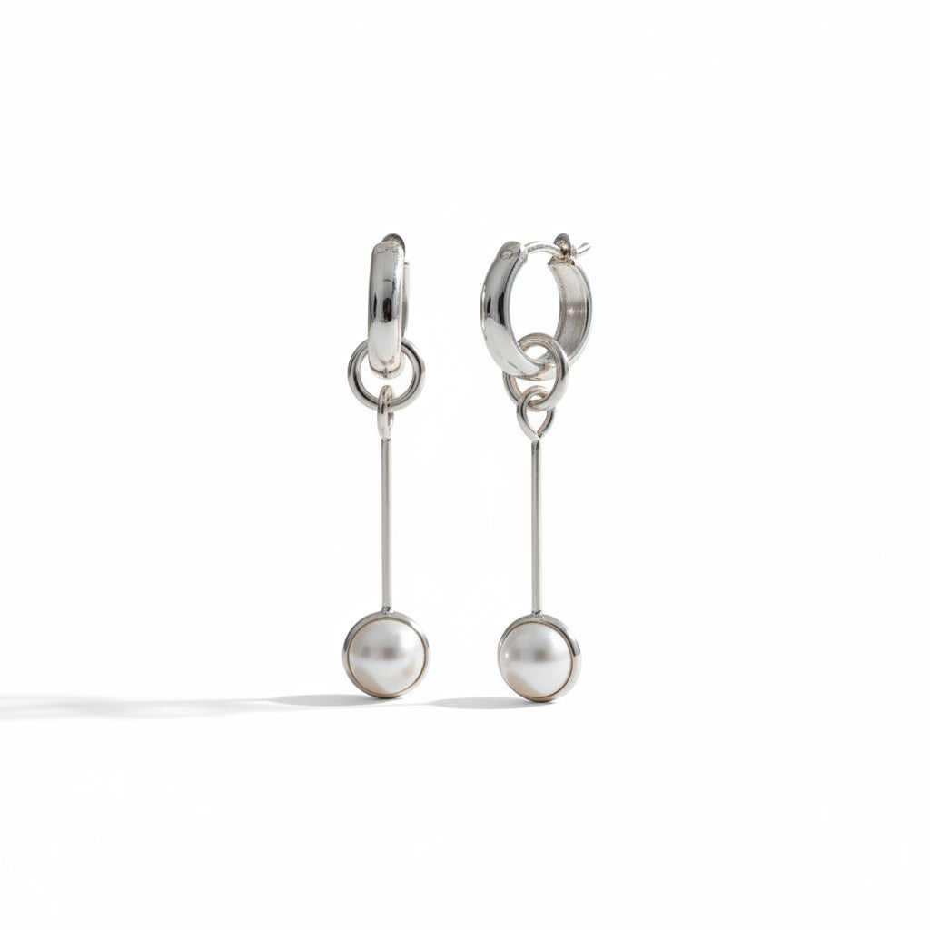 A pair of silver hoop earrings with a single drop chain ending in a small round pearl bead, photographed on a clean white background with soft shadows.